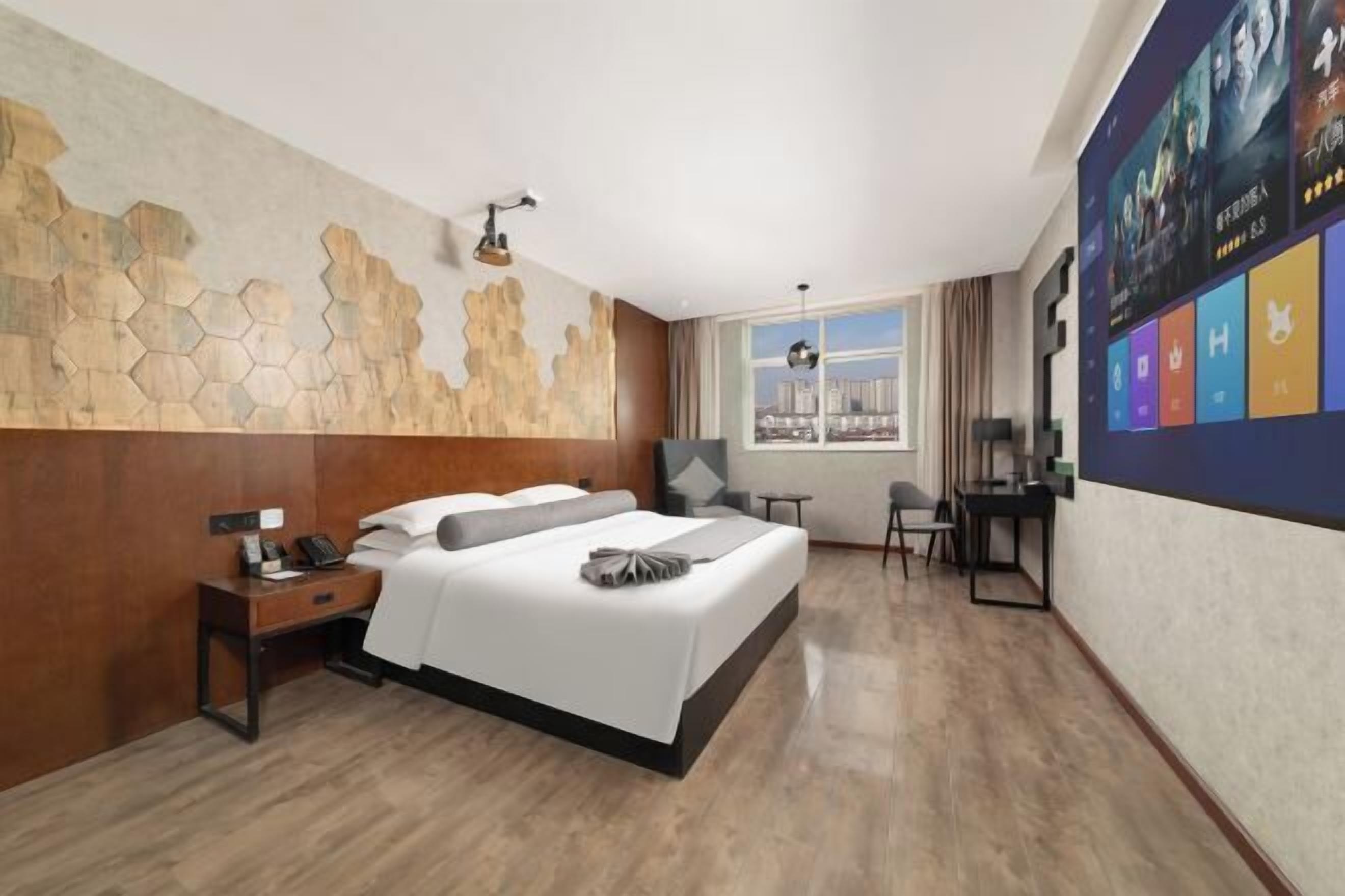 A modern hotel room with a large bed, a desk, a chair, and a view of the city through the window.