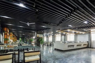Un espacio interior amplio con techos altos, una larga barra con varios puntos de servicio y diferentes distribuciones de asientos.