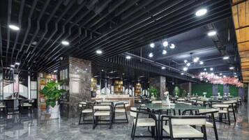 Un espacio interior amplio con varias mesas y sillas, una barra central y plantas decorativas.