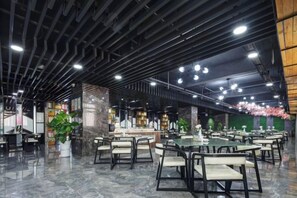 A spacious indoor area with multiple tables and chairs, a central bar area, and decorative plants. - Aoshang Hotel (Hanzhong High-speed Railway Station) (Hanzhong)