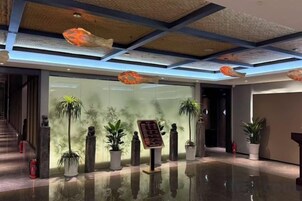 Un vestíbulo moderno con pared de vidrio, plantas en macetas e iluminación colgante en el techo.