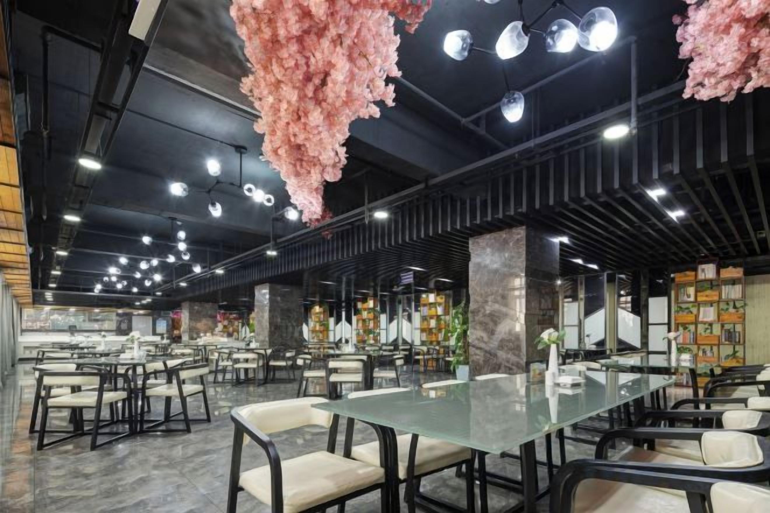 A spacious restaurant with high ceilings, hanging floral decorations, and multiple seating areas.