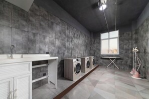 A laundry room with a white cabinet, two washing machines, and a window with a view. - Aoshang Hotel (Hanzhong High-speed Railway Station) (Hanzhong)