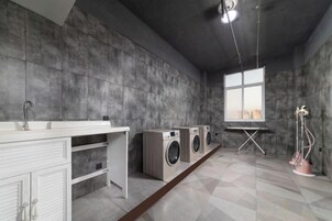 Un cuarto de lavado con un armario blanco, dos lavadoras y una ventana con vistas.