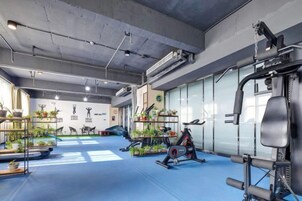 A gym with exercise equipment, mirrors, and potted plants.