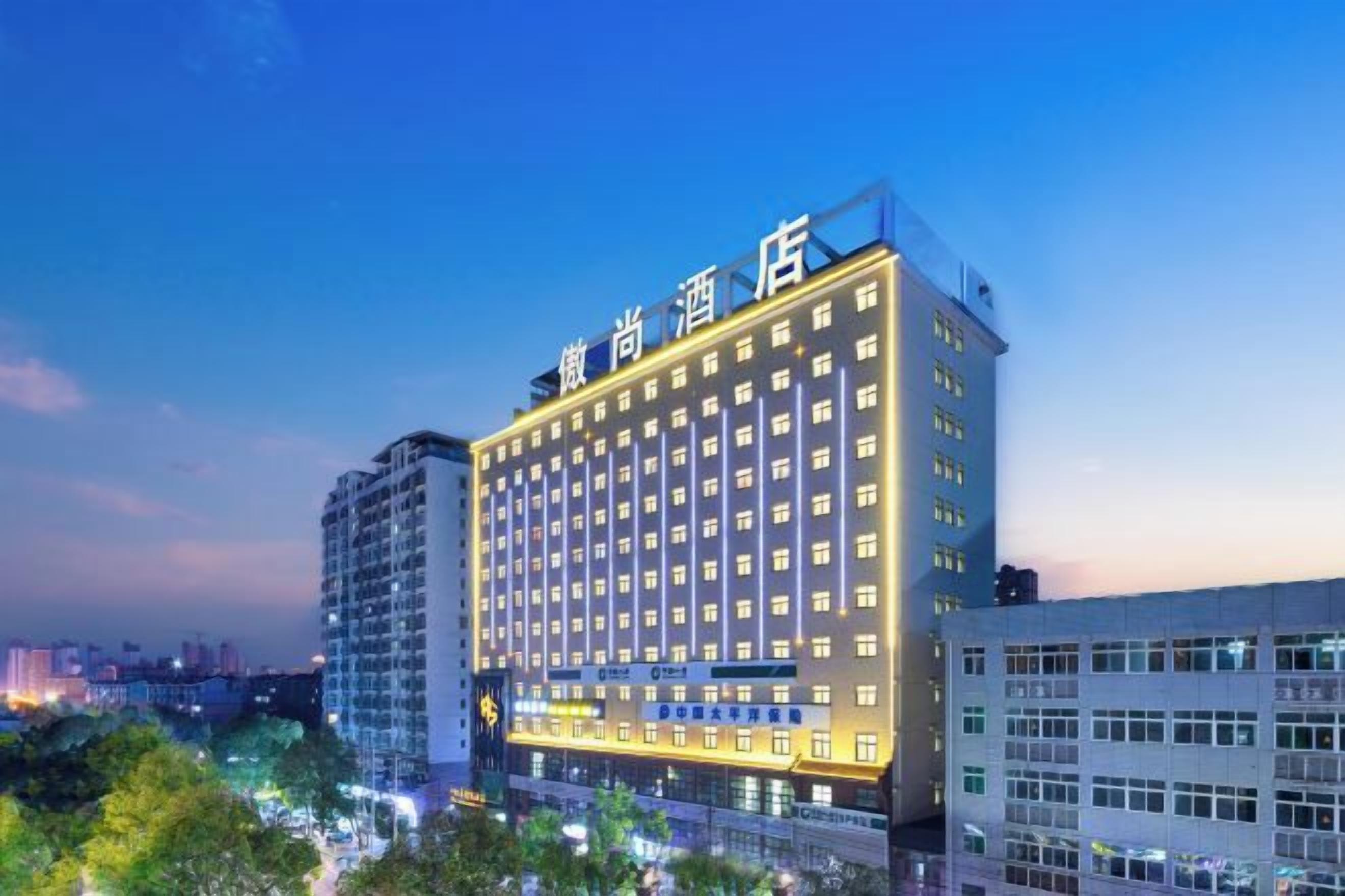 Een meerhoog hotel met een opvallend bord bovenop, tal van ramen en een modern architectonisch ontwerp.