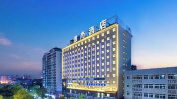 Een meerhoog hotel met een opvallend bord bovenop, tal van ramen en een modern architectonisch ontwerp.