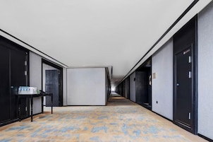 Un pasillo de hotel con piso alfombrado, una mesa con objetos encima y puertas a ambos lados.