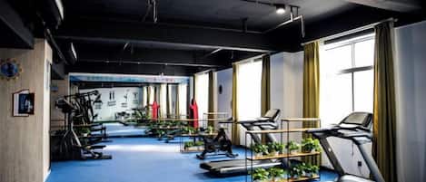 Une salle de sport équipée de tapis de course, de vélos d’appartement et d’appareils de musculation.