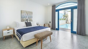 A modern bedroom with a large bed, a bedside table, a bench, and a view of an outdoor swimming pool. - Casa Posa Seminyak (Seminyak)