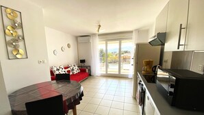A compact living space with a dining area, a kitchenette, and a balcony with a view.