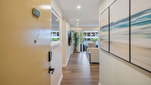 A hallway with a wooden floor, a door with a sign, and a large abstract painting on the wall.