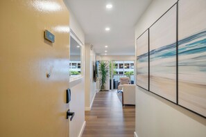 A hallway with a wooden floor, a door with a sign, and a large abstract painting on the wall.