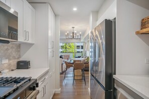 A modern kitchen with white cabinetry, a built-in gas stove, and a stainless steel refrigerator.