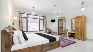 Un dormitorio con una cama de madera, un escritorio, una silla, un armario y un televisor en la pared.