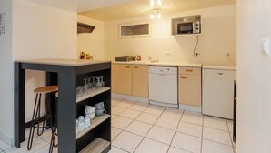 A compact kitchen with a microwave, dishwasher, and a small bar area with stools. - LE SOUVENIR D'AILLEURS T2 65m² near Futuroscope (Lhommaizé)