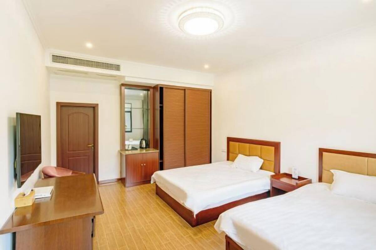 Een hotelkamer met twee bedden, een bureau, een kledingkast en een spiegel.