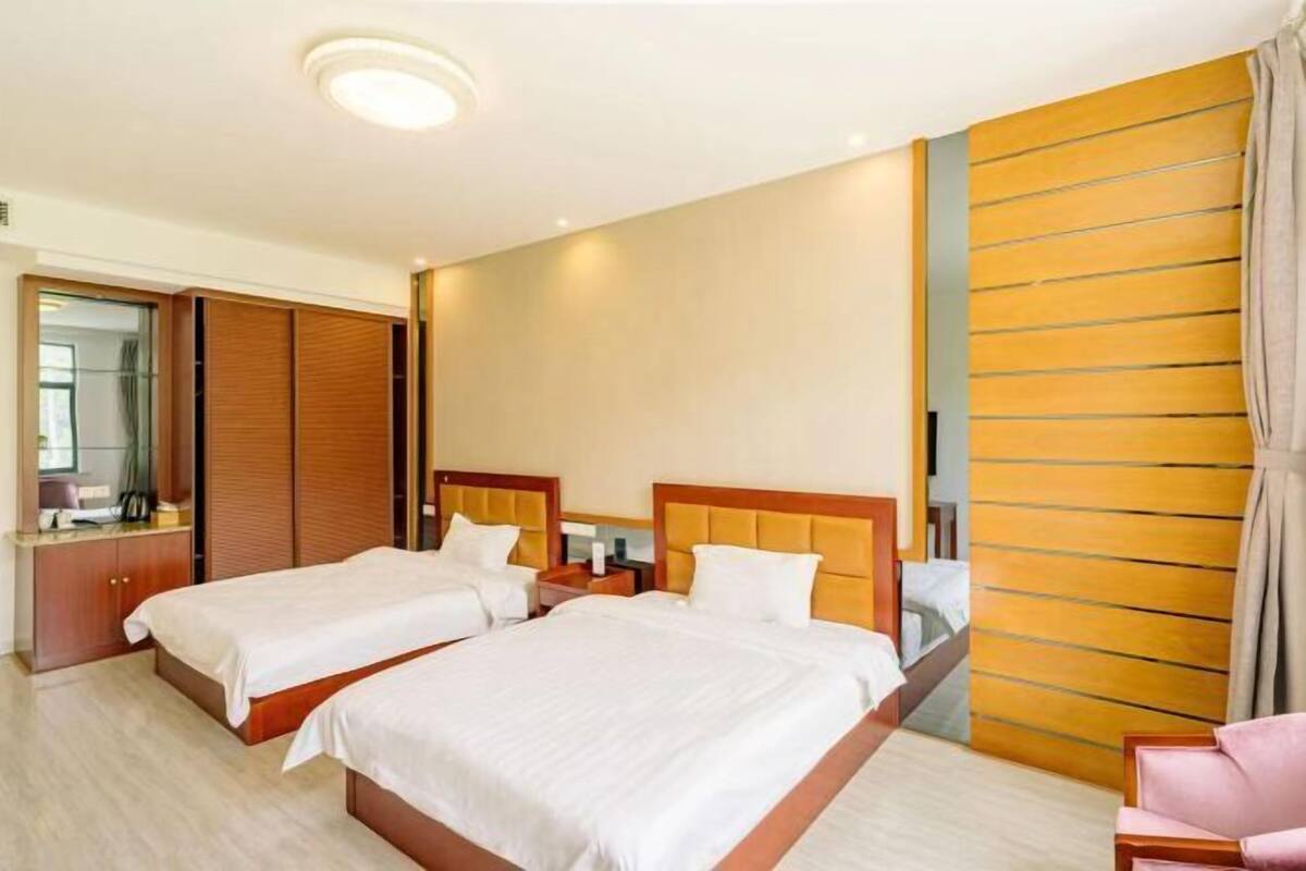 Een hotelkamer met twee bedden, een garderobe, een spiegel en een wand van hout.