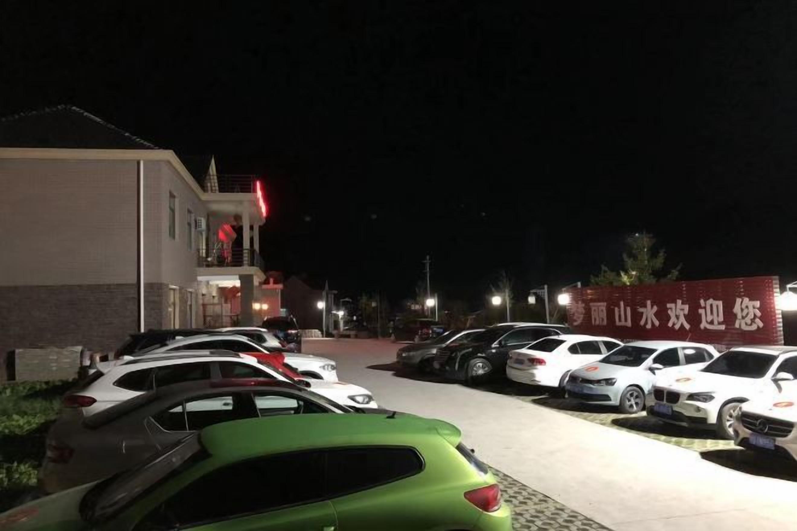 A parking lot with several cars parked in front of a building with a red sign.