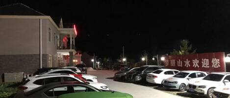 A parking lot with several cars parked in front of a building with a red sign.