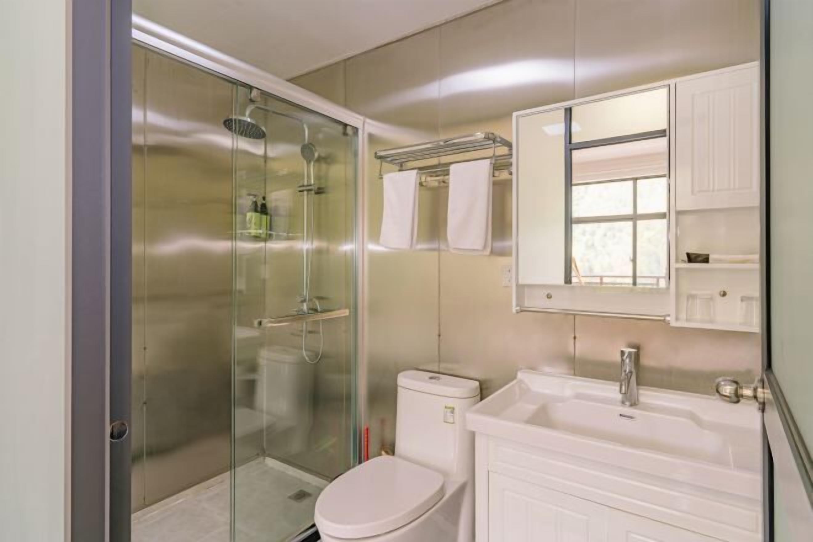 Een moderne badkamer met een douchecabine van glas, een wit toilet en een wastafel met spiegel.