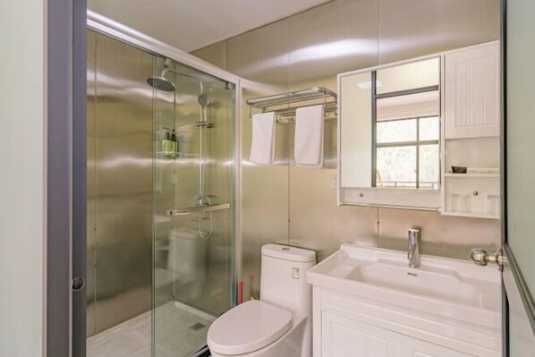 Een moderne badkamer met een douchecabine van glas, een wit toilet en een wastafel met spiegel.