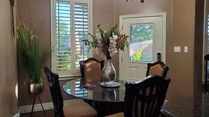 A dining area with a glass table surrounded by chairs, a vase with flowers, and a chandelier. - Cozy 2-bedroom house in Harlingen BBQ grill and back patio. (Harlingen)