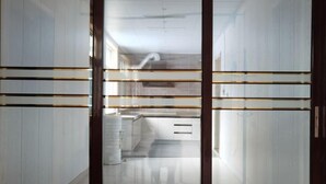 Un interior moderno con una zona de cocina, muebles blancos y un separador de vidrio.
