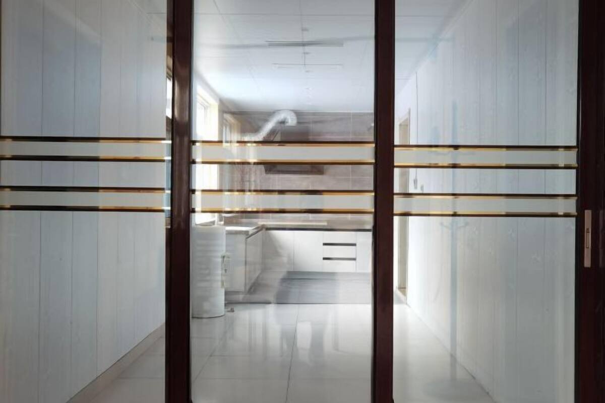 Um interior moderno com área de cozinha, armários brancos e divisória de vidro.