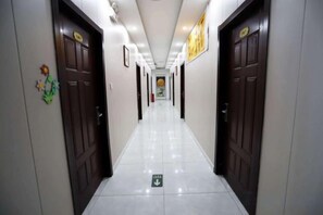 A hotel corridor with doors on either side, a tiled floor, and a directional sign at the end. - Haoping Birth House Business Hotel (Zouping)