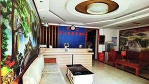 Un hall de hotel con una recepción, un reloj, un cuadro en la pared y una zona de estar.