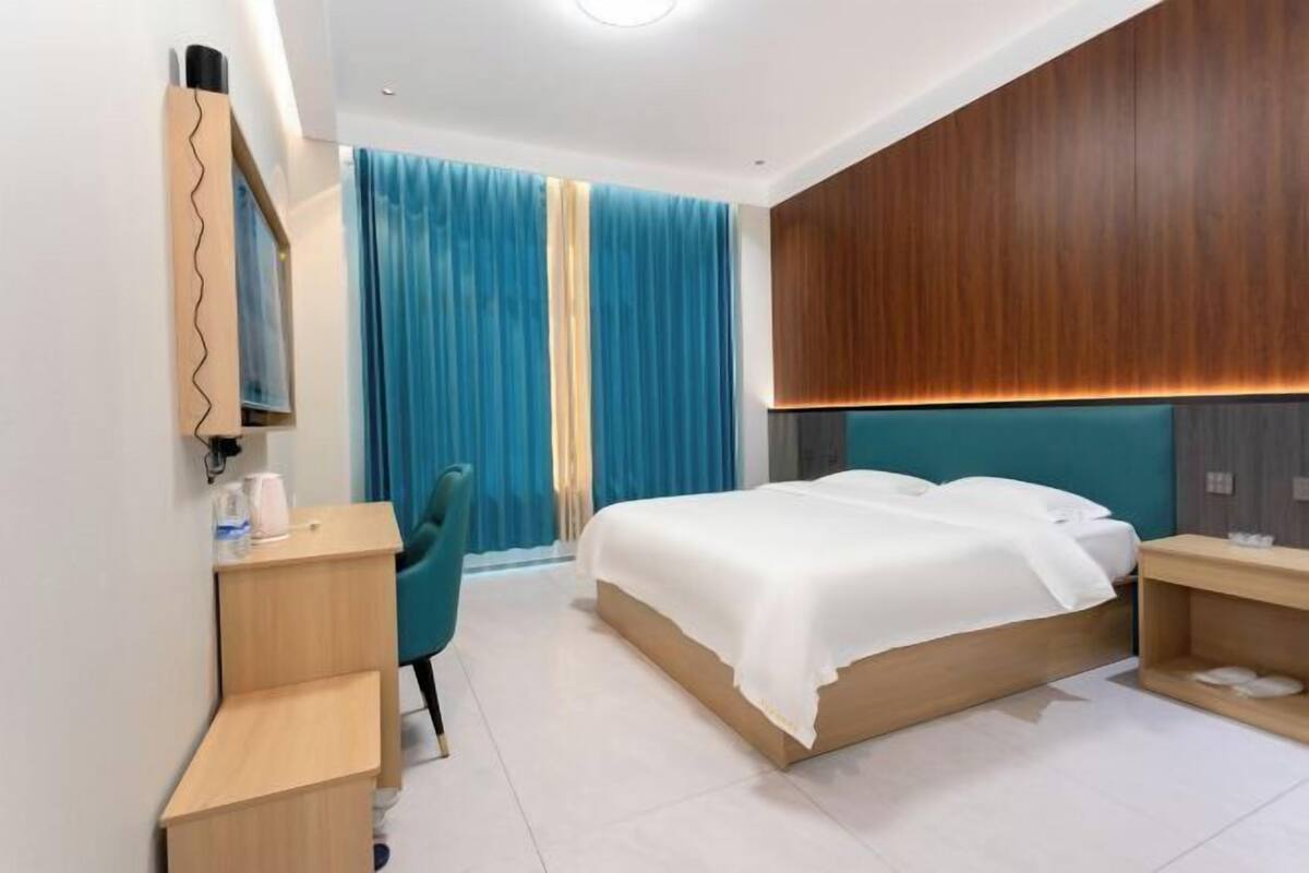 Quarto de hotel moderno com uma cama, uma escrivaninha e uma cadeira.