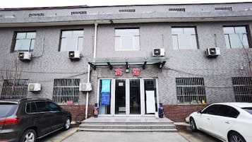 A building with a brick facade, a set of double doors, and a car parked in front.