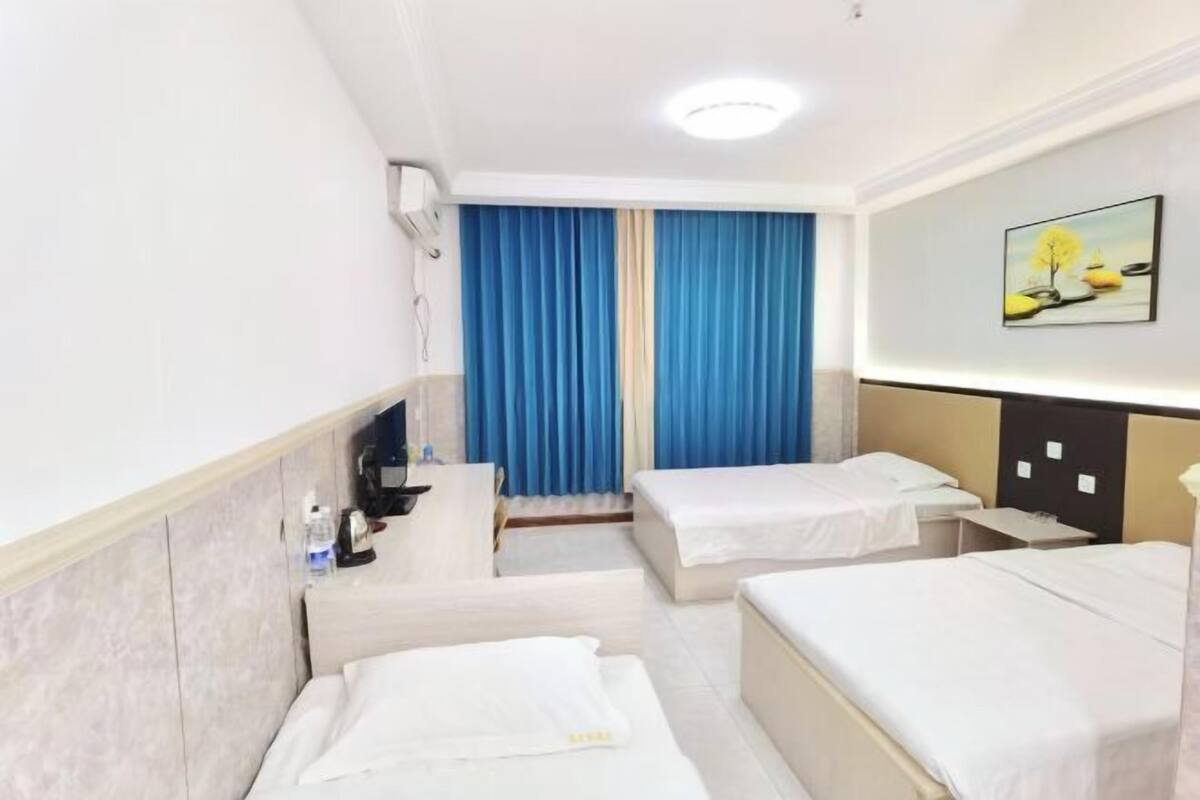 Quarto de hotel com duas camas, uma escrivaninha, uma cadeira, um espelho e um quadro na parede.