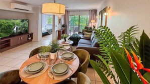 A dining area with a round table set for four, surrounded by cushioned chairs. - Leaf Luxe - 9 Pools BBQ Gym (Cairns)