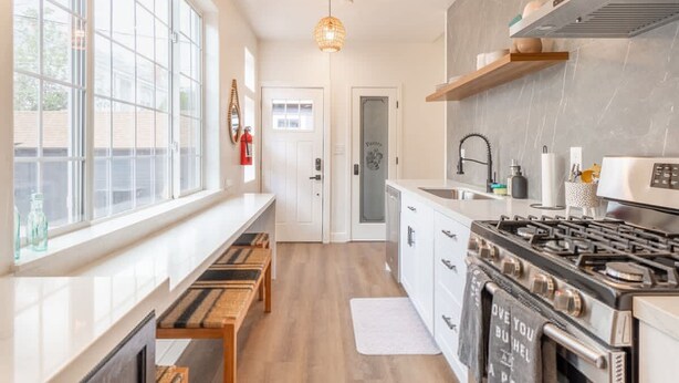 Una cocina moderna con un amplio ventanal, una estufa a gas y una lámpara colgante.