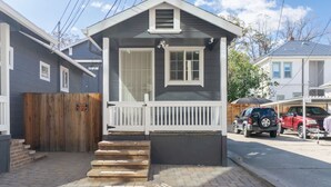 Una casa pequeña de un solo piso con un porche delantero y una valla de madera.