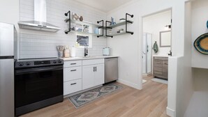 Una cocina moderna con armarios blancos, extractor de acero inoxidable y estanterías negras.