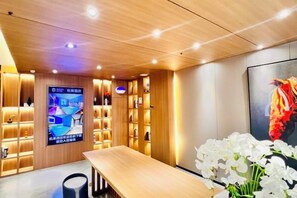 A hotel lobby with a wooden reception desk, a digital screen, and a wall with a poster. - Sangel Hotel (Zhengzhou East Longhai Road Metro Station) (Zhengzhou)