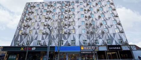 Un edificio de varios pisos con una fachada geométrica, que cuenta con una serie de ventanas y unidades de aire acondicionado.