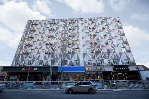 Un edificio de varios pisos con una fachada geométrica, que cuenta con una serie de ventanas y unidades de aire acondicionado.