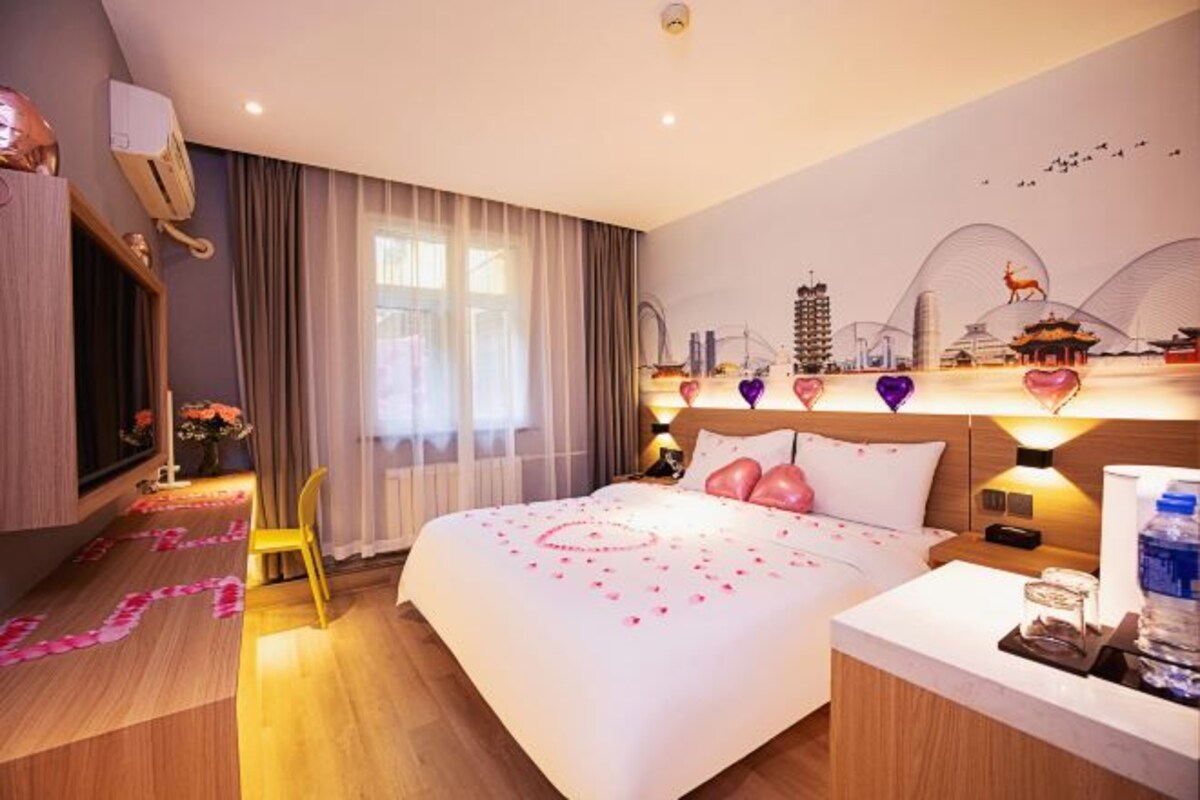 Una habitación de hotel con una cama, mesita de noche y vistas a la ciudad.