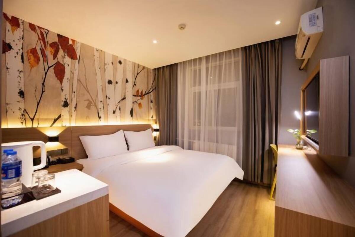 Habitación de hotel con cama, mesita de noche y aire acondicionado de pared.