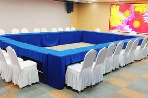 A conference room with a long table, white chairs, and a floral wall decoration. - Sangel Hotel (Zhengzhou East Longhai Road Metro Station) (Zhengzhou)