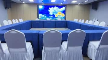 A conference room with a large oval table, white chairs, and a screen displaying a floral image.