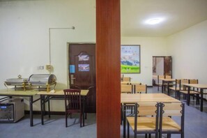 A dining area with tables and chairs, a refrigerator, and a wall-mounted television. - Holiday Inn Lijiang Langtai (Lijiang)
