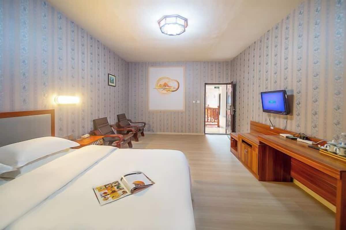 Una habitación de hotel con una cama, un escritorio, un televisor y una puerta que da a un balcón.