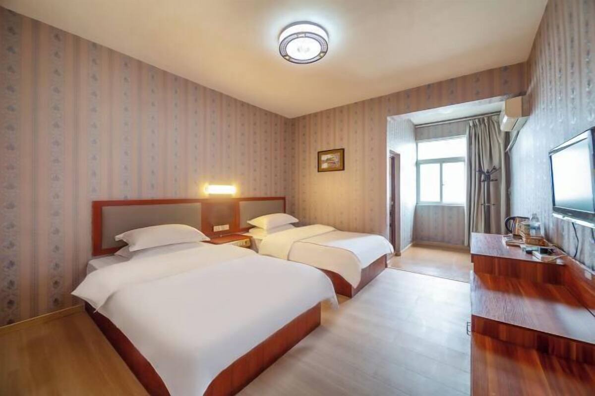 Habitación de hotel con dos camas, un escritorio, un televisor y una ventana.