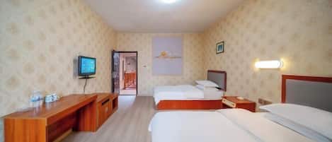 A hotel room with a wooden desk, two beds, a television, and a painting on the wall.