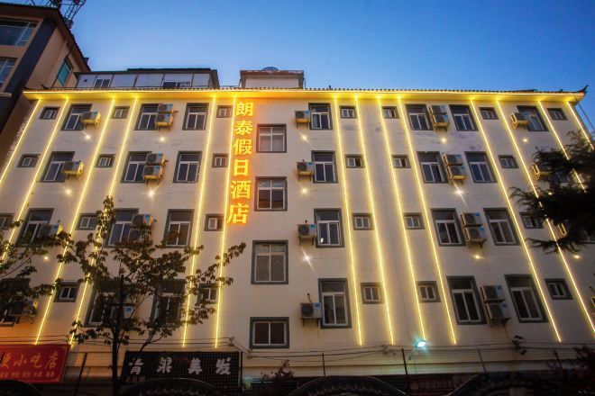 Un edificio de hotel de varios pisos con líneas verticales iluminadas en la fachada, múltiples ventanas y un letrero con caracteres chinos.